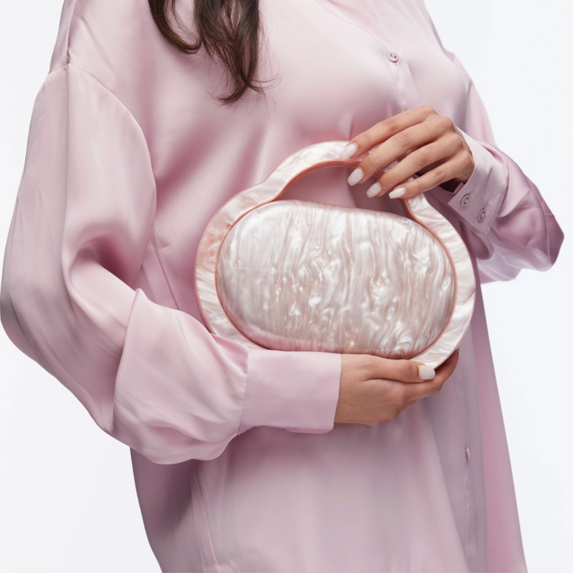 Person holding a pearlized clutch bag against a white background
