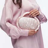 Person holding a pearlized clutch bag against a white background