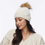 Woman wearing a white knit beanie with a fur pom-pom on a white background