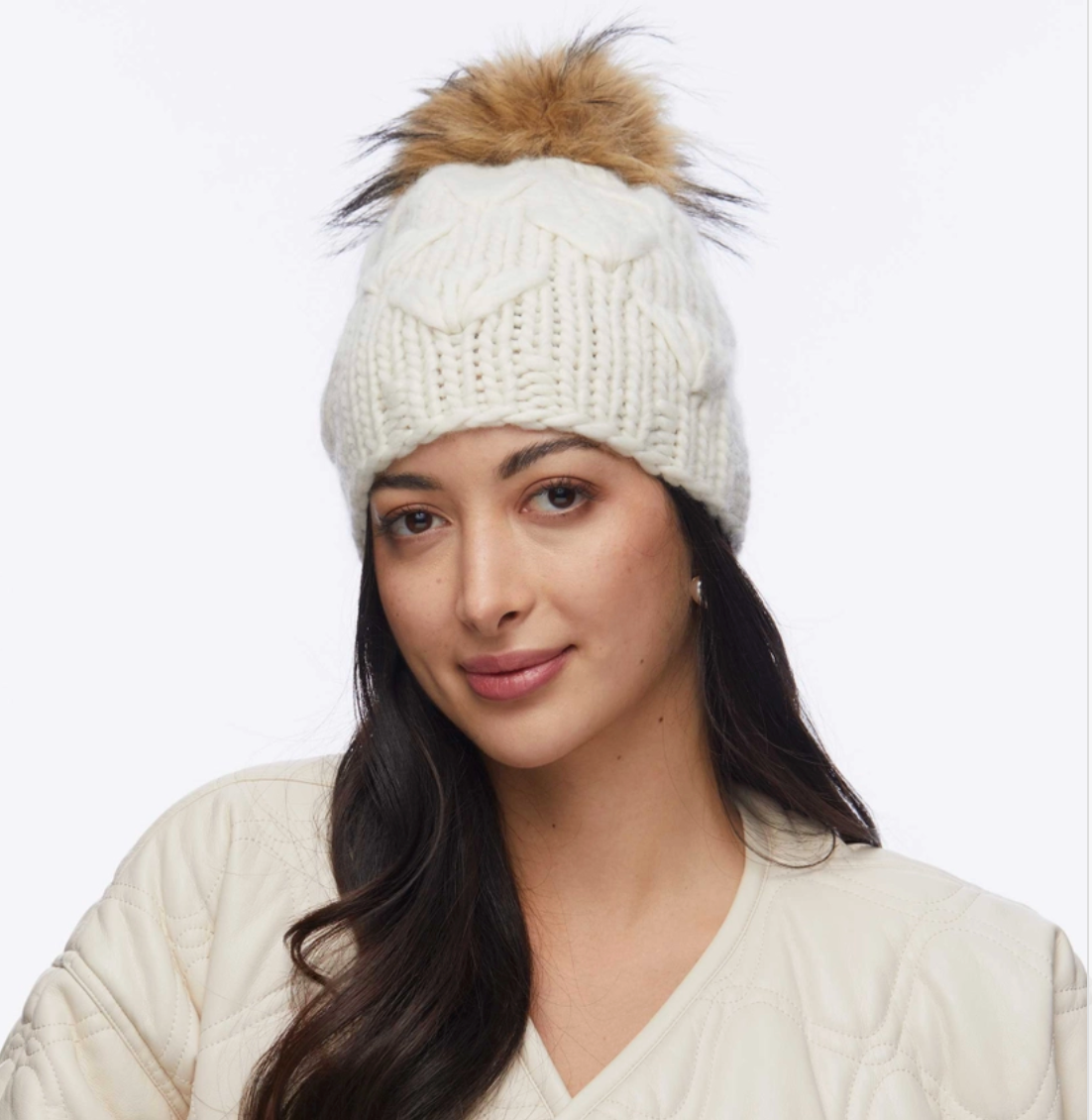 Woman wearing a white knit beanie with a fur pom-pom on a white background