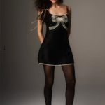 Woman wearing a black dress with a large bow on a gray background