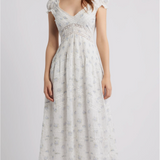 Woman wearing a white floral dress on a plain background