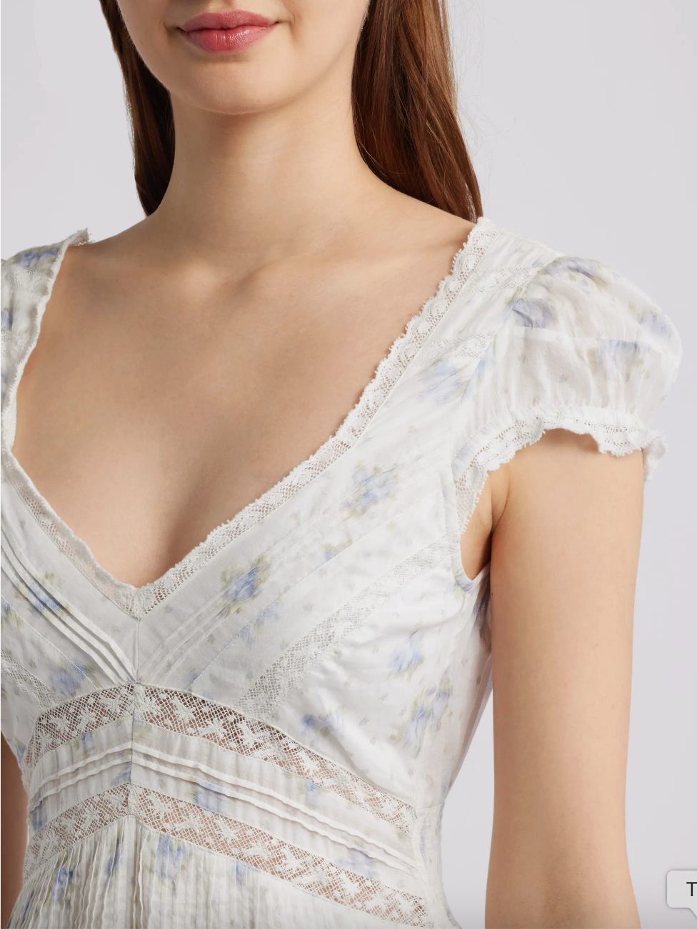 White lace dress with floral patterns on a plain background