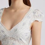 White lace dress with floral patterns on a plain background