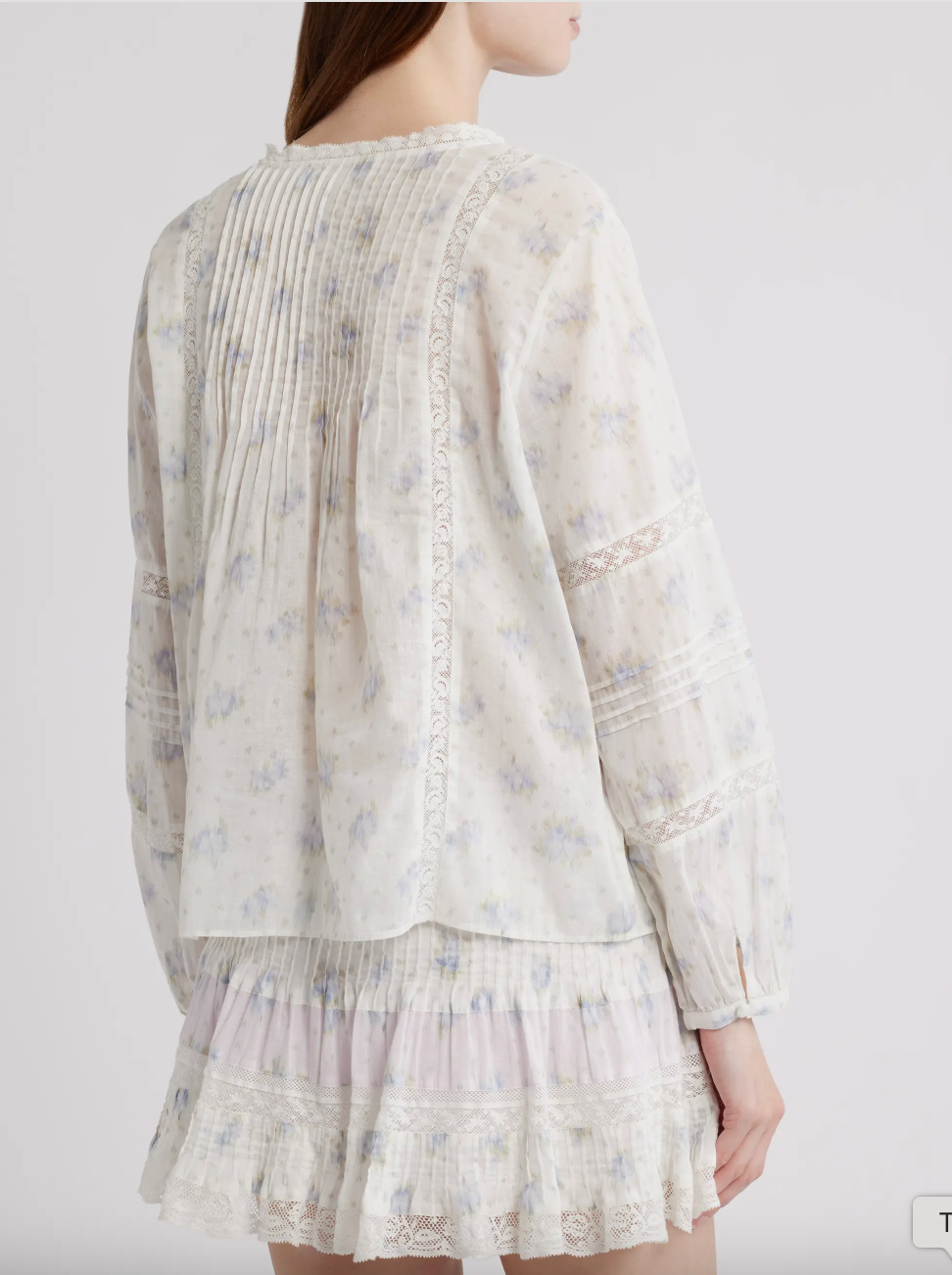 Light-colored long sleeve top and mini skirt with floral pattern on a plain background