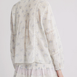 Light-colored long sleeve top and mini skirt with floral pattern on a plain background