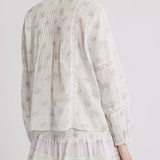 Light-colored long sleeve top and mini skirt with floral pattern on a plain background