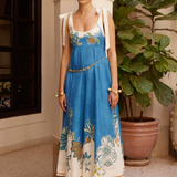 Woman wearing a blue floral dress standing in an indoor setting with plants.