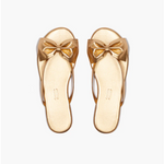 Pair of gold sandals with bow details on a white background