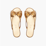 Pair of gold sandals with bow details on a white background