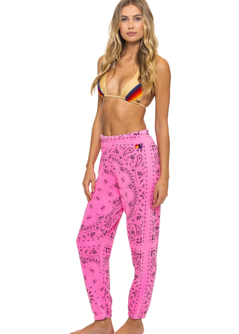 Woman wearing a colorful bikini top and pink patterned pants on a white background