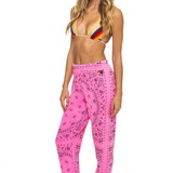 Woman wearing a colorful bikini top and pink patterned pants on a white background