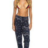 Woman wearing a bikini top and charcoal patterned pants on a white background