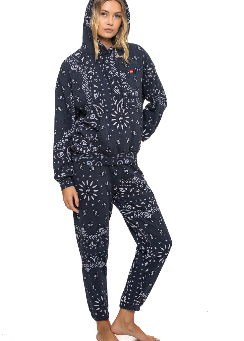 Person wearing a charcoal sweat pants and hoodie with white patterns on a white background 