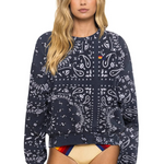 Woman wearing a charcoal patterned sweatshirt with a colorful swimsuit underneath on a white background