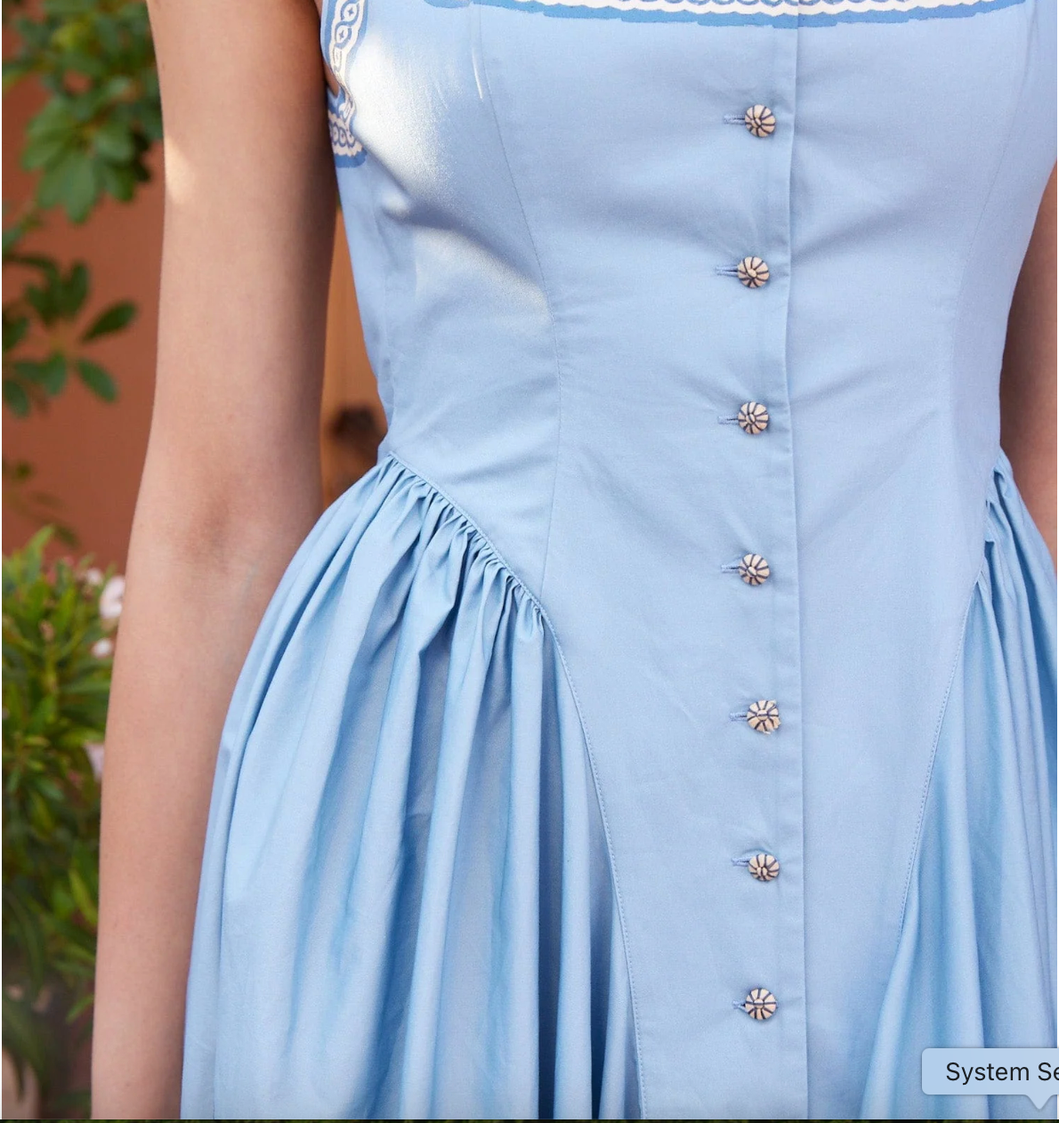 Light blue dress with decorative buttons on a blurred background