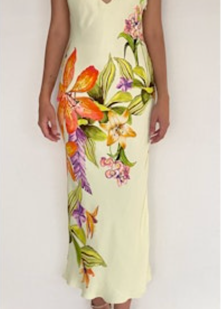Woman wearing a light yellow slip dress with colorful floral pattern against a white background