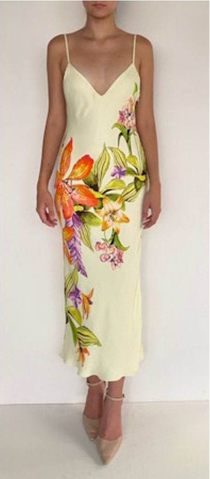 Woman wearing a light yellow slip dress with colorful floral pattern against a white background