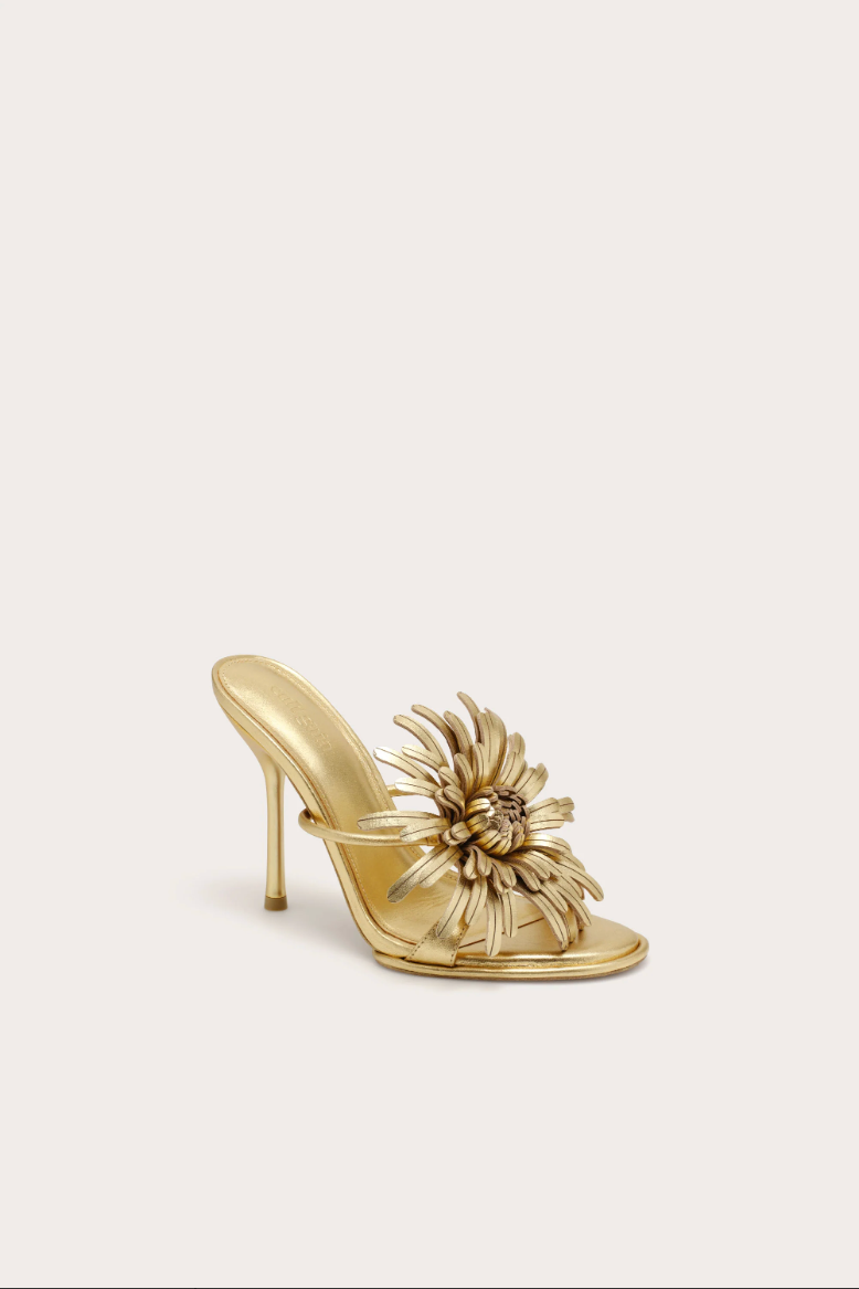 Gold high-heeled shoe with floral design on a light beige background