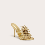 Gold high-heeled shoe with floral design on a light beige background