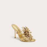 Gold high-heeled shoe with floral design on a light beige background