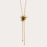 Gold bolo necklace with large flower on a plain background