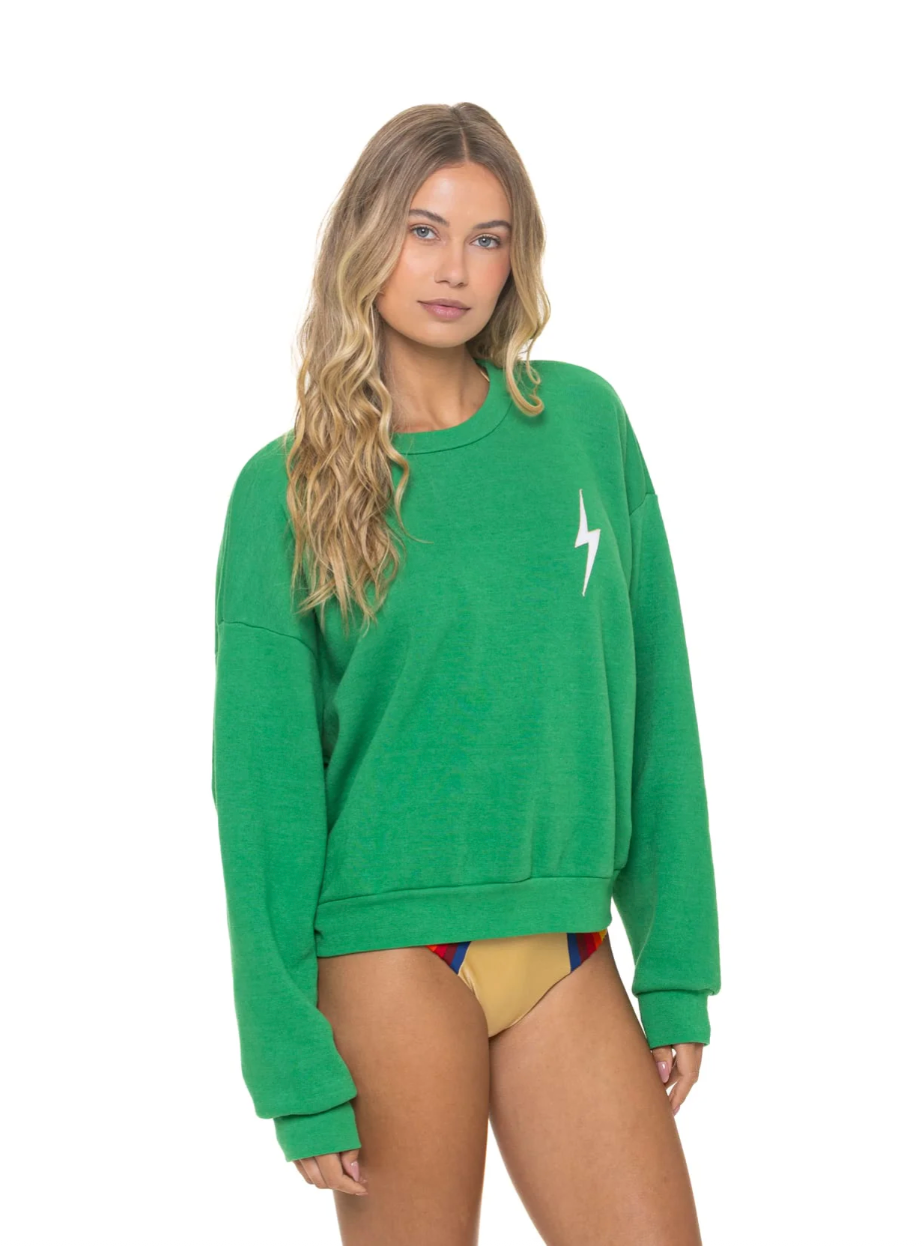 Woman wearing a green sweatshirt with a white logo on a white background