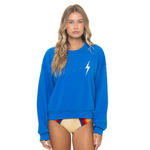 Woman wearing a blue sweatshirt with a white lightning bolt design on a white background