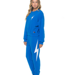 Woman wearing a blue sweatshirt and pants with a lightning bolt design on a white background