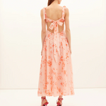 Woman wearing a pink floral dress with a white background