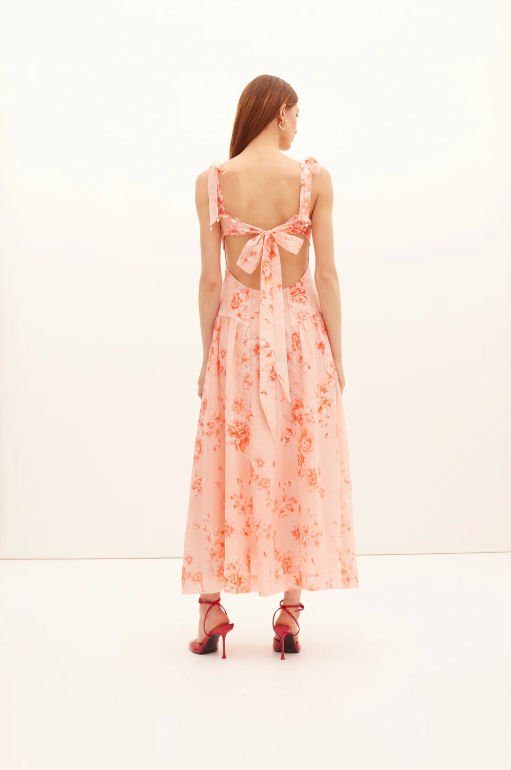 Woman wearing a pink floral dress with a white background