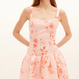 Woman wearing a pink floral dress against a white background