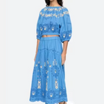 Woman wearing a blue embroidered outfit on a white background