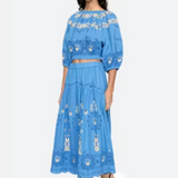 Woman wearing a blue embroidered outfit on a white background