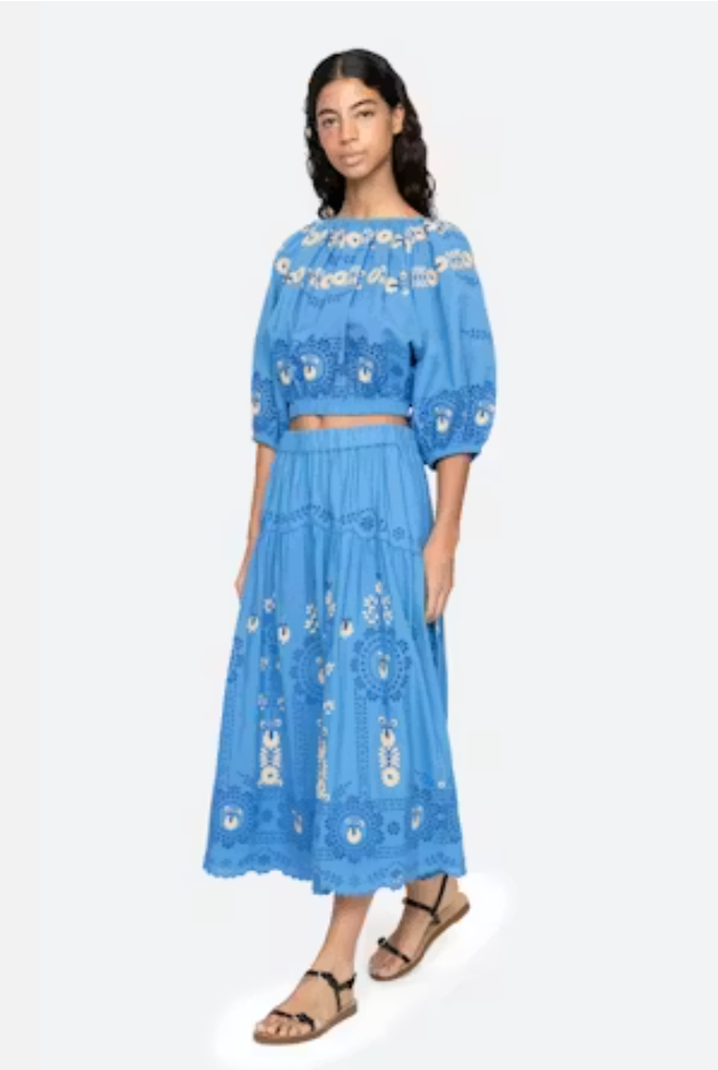 Woman wearing a blue embroidered outfit on a white background