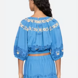 Woman wearing a blue embroidered top and skirt set on a white background