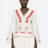Woman wearing a white outfit with red embroidery on a white background