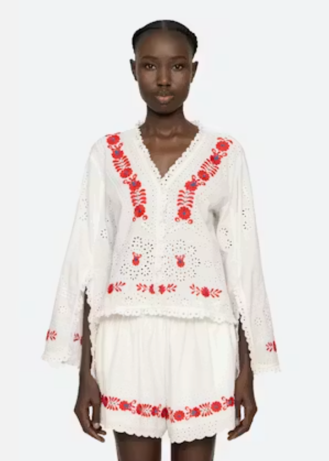 Woman wearing a white outfit with red embroidery on a white background