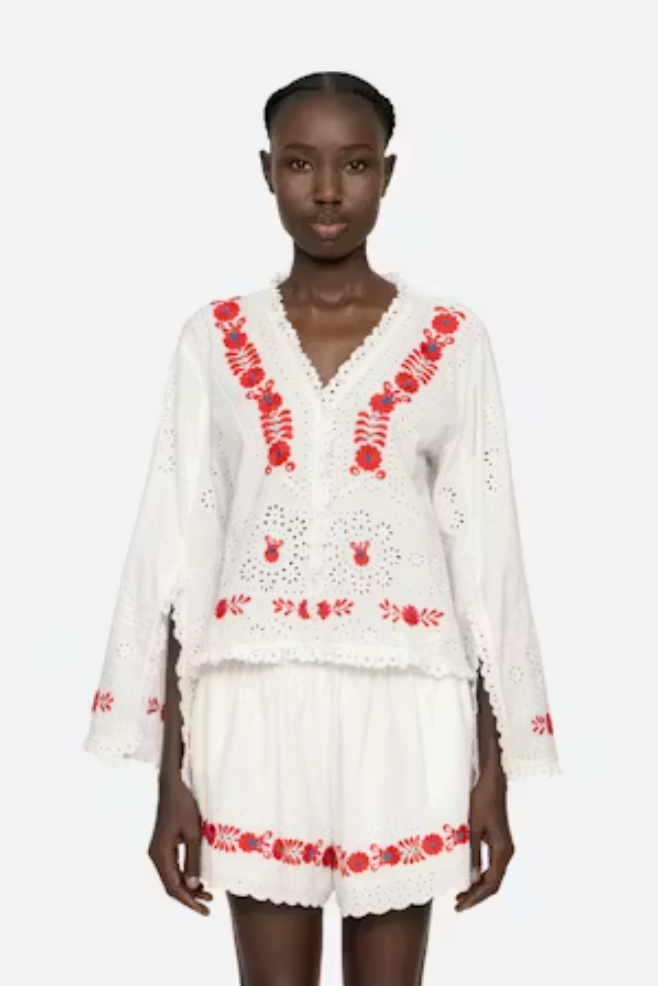 Woman wearing a white outfit with red embroidery on a white background