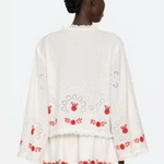 White embroidered dress with red patterns on a white background