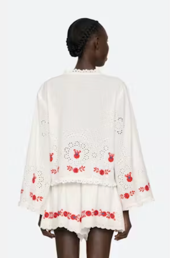 White embroidered dress with red patterns on a white background