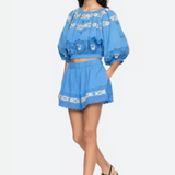 Woman wearing a blue embroidered outfit on a white background