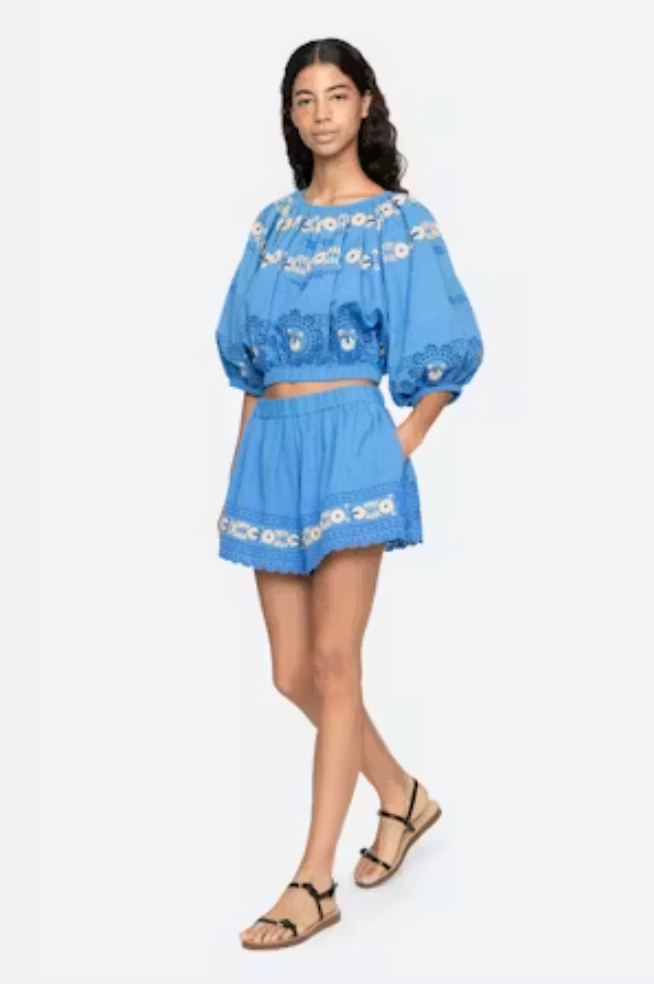 Woman wearing a blue embroidered outfit on a white background
