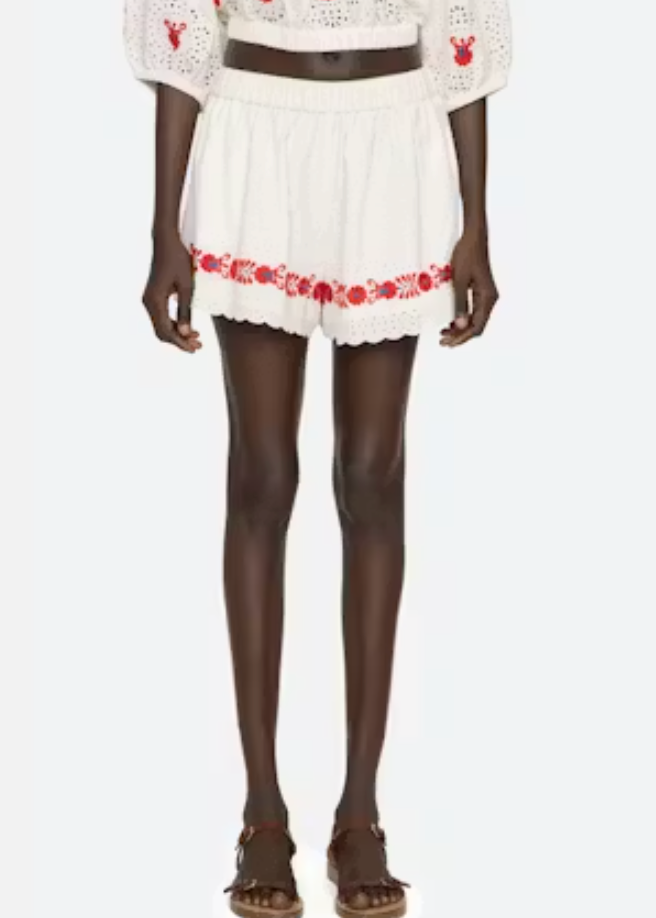 White outfit with red floral embroidery on a white background