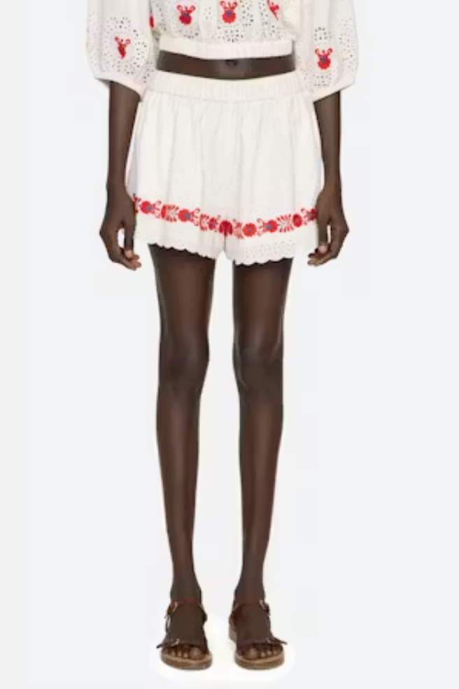 White outfit with red floral embroidery on a white background