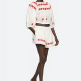 Model wearing a white outfit with red embroidery on a white background