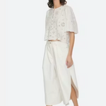 Woman wearing a white outfit with a floral top and wide-leg pants on a white background