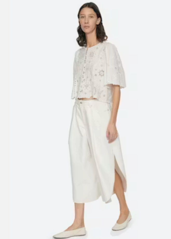 Woman wearing a white outfit with a floral top and wide-leg pants on a white background