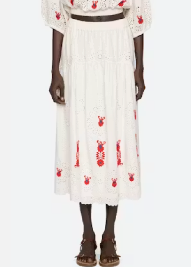 Person wearing a white dress with red patterns on a white background