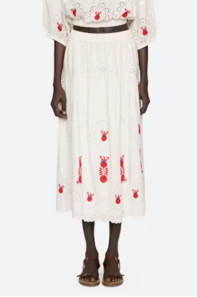 Person wearing a white dress with red patterns on a white background